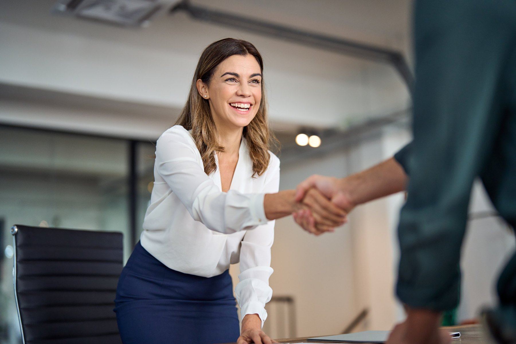 A smiling attorney shaking hands with a client across her desk